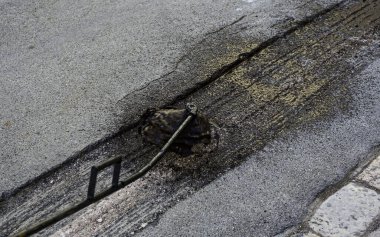 Asfalt yolun kısmi onarımı. İşçi asfalt yüzeyine zift püskürtür. Yol bakım işçisi zifti temizleyiciye püskürtür.