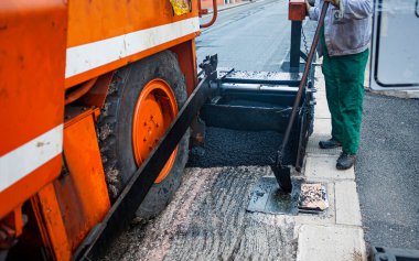 İşçi, asfalt döşeyen kaldırımları düzenler 160 derecenin üzerindeki sıcaklıklara kadar ısıtır.