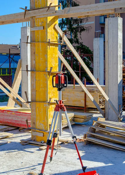 Total center device on tripod with laser for leveling other devices to level construction site.