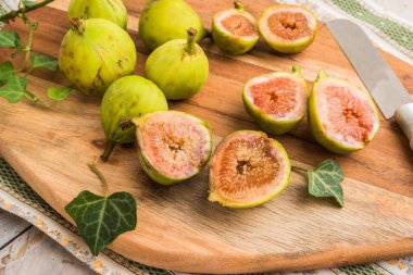 Hasır sepet bir rustik ahşap masa üstünde bütün incir.