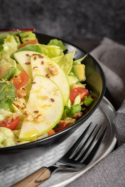 Salata. Bahar sebze salatası. Domatesli, elmalı, fındıklı, tohumlu ve limonlu taze sebze salatası. Salata kasesine zeytin yağı dökülüyor.