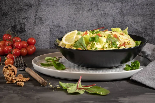 Salata. Bahar sebze salatası. Domatesli, elmalı, fındıklı, tohumlu ve limonlu taze sebze salatası. Salata kasesine zeytin yağı dökülüyor.