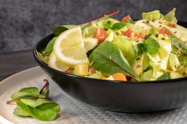 Salata. Bahar sebze salatası. Domatesli, elmalı, fındıklı, tohumlu ve limonlu taze sebze salatası. Salata kasesine zeytin yağı dökülüyor..