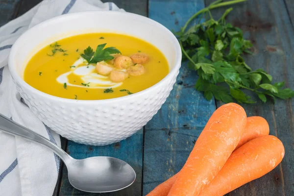 Krem ve ahşap zemin üzerine maydanoz ile havuç çorbası. Kopya alanı