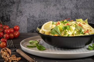 Salata. Bahar sebze salatası. Domatesli, elmalı, fındıklı, tohumlu ve limonlu taze sebze salatası. Salata kasesine zeytin yağı dökülüyor..