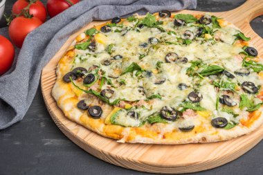 Ev yapımı vejetaryen pizza ıspanak, domates, Siyah Zeytin ve mozzarella peyniri pişirme Pan ile ahşap arka plan üzerinde pişmiş.