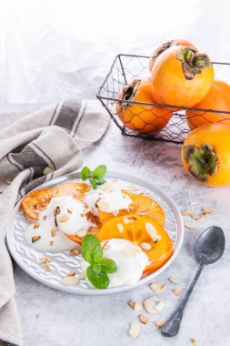 Yoğurt ve badem ile dilimlenmiş Trabzon hurması. Açık renkli sağlıklı gıda konsepti