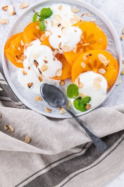 Yoğurt ve badem ile dilimlenmiş Trabzon hurması. Sağlıklı gıda kavramı o