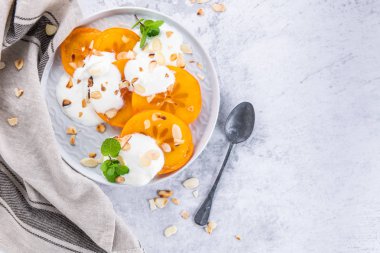 Yoğurt ve badem ile dilimlenmiş Trabzon hurması. Sağlıklı gıda kavramı üzerinde açık renkli. üstten görünüm