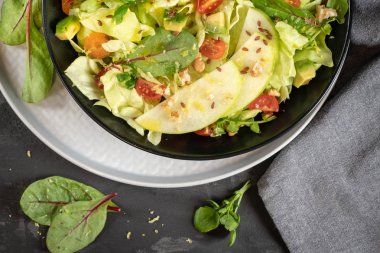 Salata. Bahar sebze salatası. Domatesli, elmalı, fındıklı, tohumlu ve limonlu taze sebze salatası. Salata kasesine zeytin yağı dökülüyor.