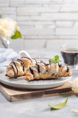 Leziz continental kahvaltı taze lapa lapa Fransız kruvasan ve kahve, kruvasan kapatın. Hafif bir arka plan üzerinde beyaz Kamelya çiçeklerle. Provence rustik tarzı.