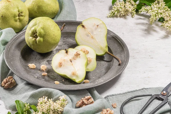 Peras saborosas com nozes. Uma mesa decorada com flores e um prato de peras cortadas na placa . — Fotografia de Stock