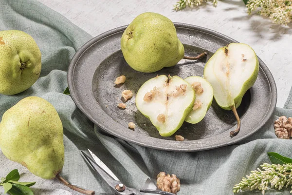 Leckere Birnen mit Nüssen. ein Tisch mit Blumen und einem in den Teller geschnittenen Teller mit Birnen. — Stockfoto