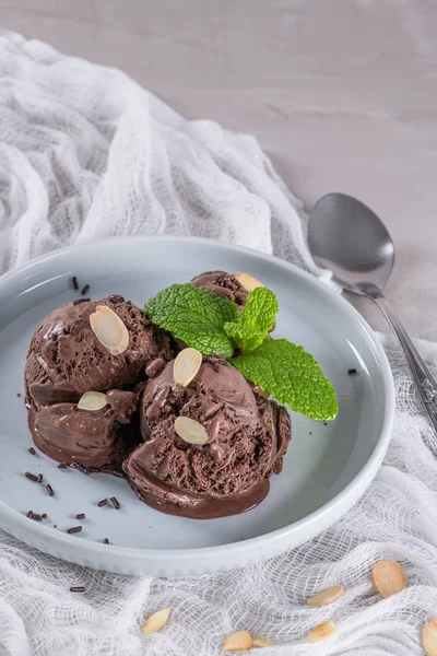 Piatto di gelato al cioccolato con fette di mandorla e foglie di menta — Foto Stock