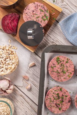 Pancar ve maydanoz yaprakları ile beyaz fasulye ile ham vejetaryen burger ahşap kesme tahtası üzerinde bırakır. üst görünüm