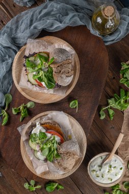 Rustik mutfak tezgahı üst taze sebze ve yoğurt soslu sağlıklı vegan burger. Üstte görüntü