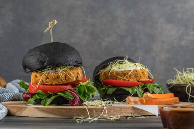 Lezzetli ızgara vejetaryen burger, nohut ve ahşap arka planda siyah ekmek üzerine sebze.