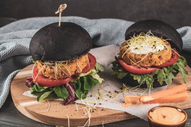 Lezzetli ızgara vejetaryen burger, nohut ve ahşap arka planda siyah ekmek üzerine sebze.