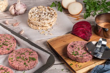 Çiğ vejetaryen burger pancar kökü ve maydanoz yapraklı beyaz fasulye tahta kesme tahtasında.