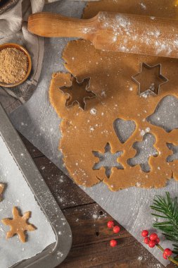 Zencefilli kurabiye yapıyorum. Çiğ hamur, zencefilli çörek adam, noel ağacı, yıldız, kırsal masada kağıt üzerinde kar taneleri merdaneli iğne. Pişirme için hazırlanılıyor