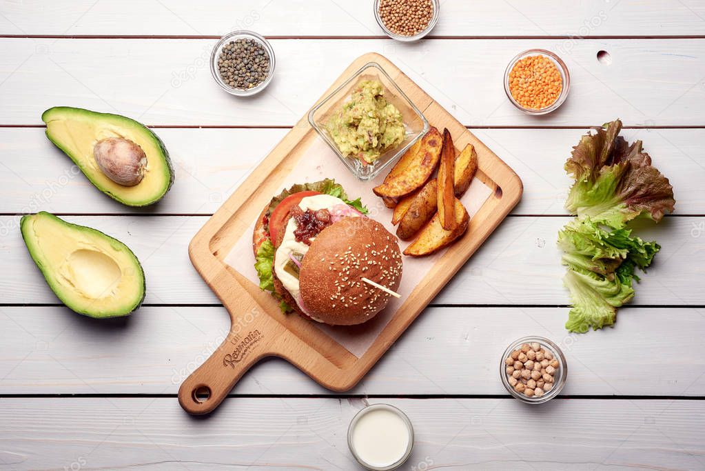 The Burger and the fresh ingredients on the old Board. On a white chalkboard. Top view.