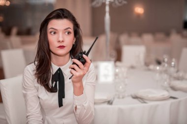 Young woman with transmitter in her hand sitting on blur background with light bokeh of dinning place. looking apart