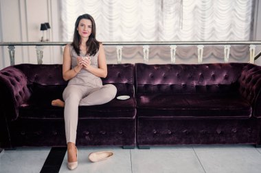 Düşünceli kadın kanepede otururken evde gülümseyerek kahve fincanı tutan. kopyalama alanı