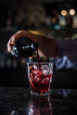 Alkollü içki şişe suyu ve buz küpleri ile kokteyl cam içine dökme barmen