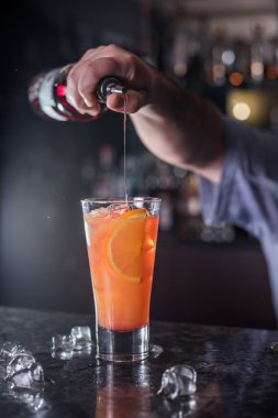 profesyonel barmen hazırlar ve bir bar arka plan üzerinde bir şişe den kırmızı şurubu dökülen kokteyller karışımları
