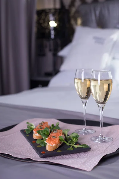 Luxury hotel room with a table with snacks and champagne glasses close up