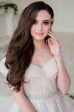 Gelinliğin yanında genç ve güzel bir gelin düğün saç stili, sarı saç, gelinlik, makyaj hazırlıyor. Kapalı çekim