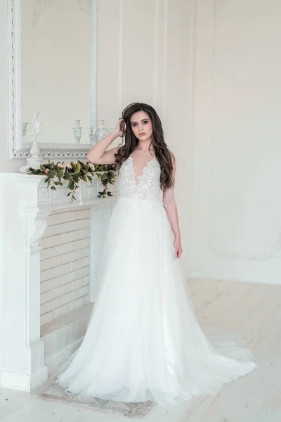 Тонка красива жінка в розкішній весільній сукні біля квітів у кімнаті — стокове фото