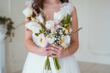 Beyaz bir duvar a yakın odada bir çiçek buketi ile güzel esmer gelin