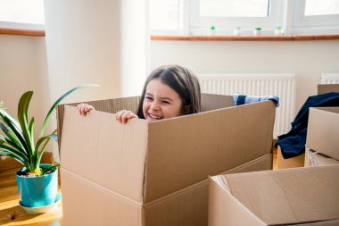 Kutudaki mutlu kız çocuğu taşınma günü ya da taşınma günü için heyecanlı, neşeli kız yeni evinde bavulunu boşaltma oyunu oynuyor eğleniyor.