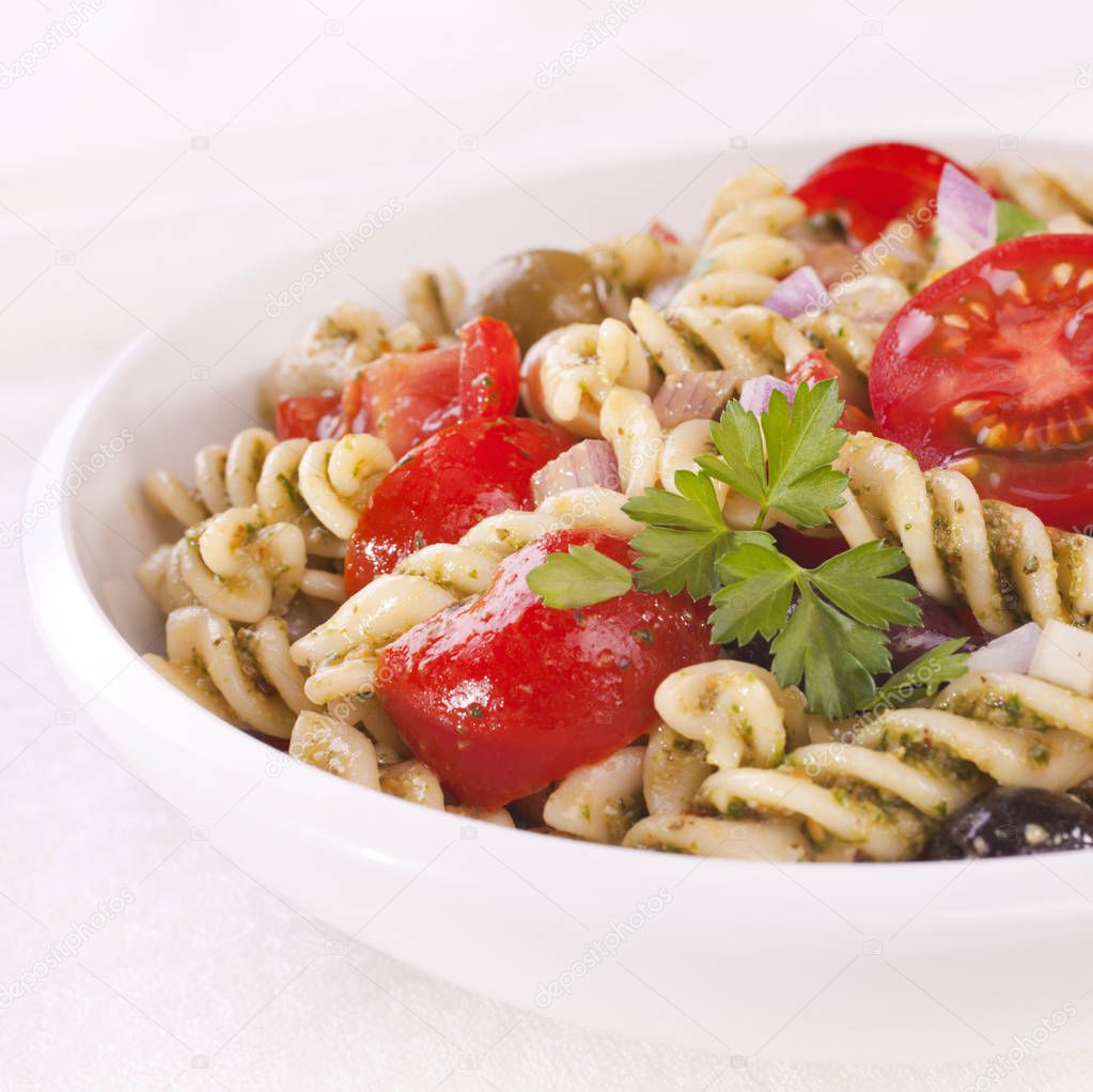 Fusili pasta salad, with rocket pesto, juicy tomatoes, olives and onion.