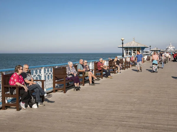 Idosos Relaxando no cais de Llandudno em outubro Sunshine — Fotografia de Stock