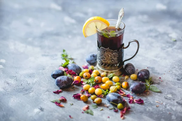 bir bardak çay limon ve dağınık meyveler - mavi ve Sarı Erik