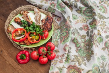 bir tabak pişmiş et, peynir ve sebze ahşap bir masa üzerinde. Vintage süsleme ile tekstil masa örtüsü