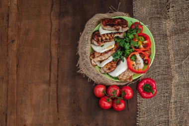 bir tabak pişmiş et, peynir ve sebze ahşap bir masa üzerinde. Çuval bezi kumaştan çevre masa örtüsü