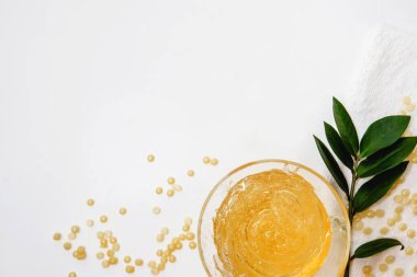  Şekerleme macunu, granüller, beyaz havlu ve yeşil dal. Beyaz arkaplanda kopyalama alanı olan düz bir düzen.