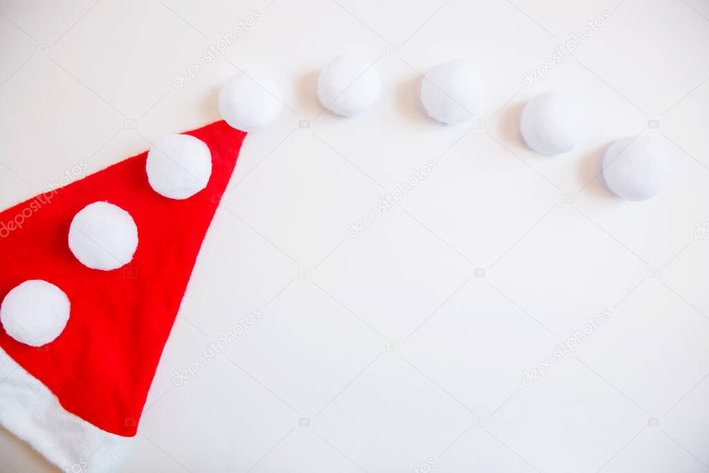 Santa Claus hat and lots of white balls on a white background. Christmas flat layout with space for text. High quality photo