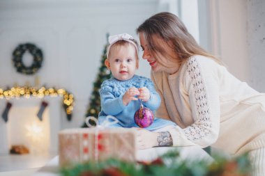 Masadaki parlak bir odada örgü elbiseli bir anne. Noel atmosferi - şömine, hediyeler, bokeh.