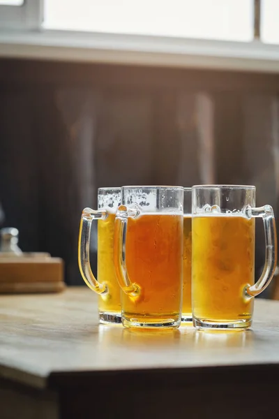 Four glasses of light beer in a bar on a wooden table