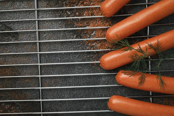 Few fresh sausages on a metal grill before baking, top view. Food background