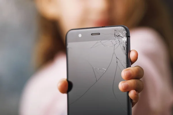 Broken phone in hands of small child, close-up