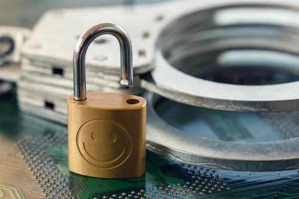 Digital security concept: Open lock on computer chip background with handcuffs