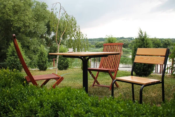 Three chairs and a table in the garden near the river