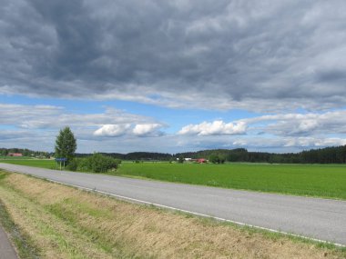 Finlandiya ülke: yol, yeşil çim ve orman, gre bulutlar ile mavi gökyüzü