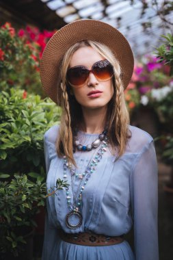 şapka ve gözlük renkli çiçekler arka plan üzerinde poz sarışın kadın 