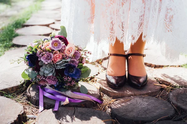 Close-up of bride feet in stylish shoes and wedding bouquet on ground